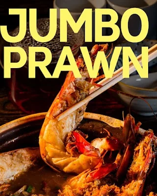 Close-up of a jumbo prawn lifted from a claypot broth
