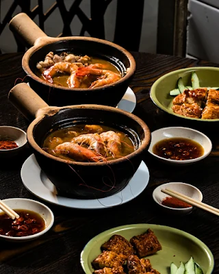 Claypot bowls of prawn noodles arranged on a dining table